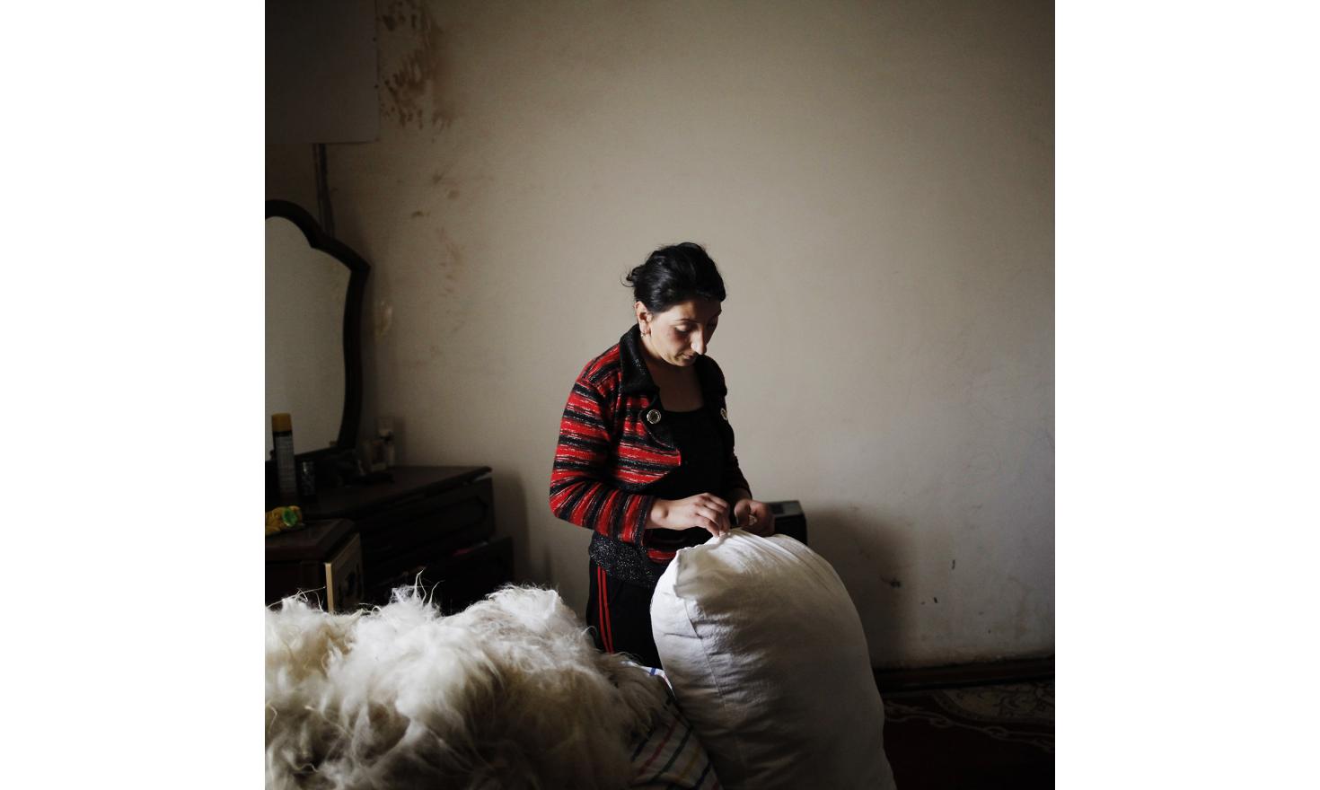 Early in the morning, Ruzanna prepares bed mattress for her children with sheep wool bought a few days ago.