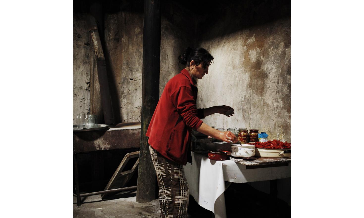Anoush is preparing canned peppers in the outbuilding of the house.