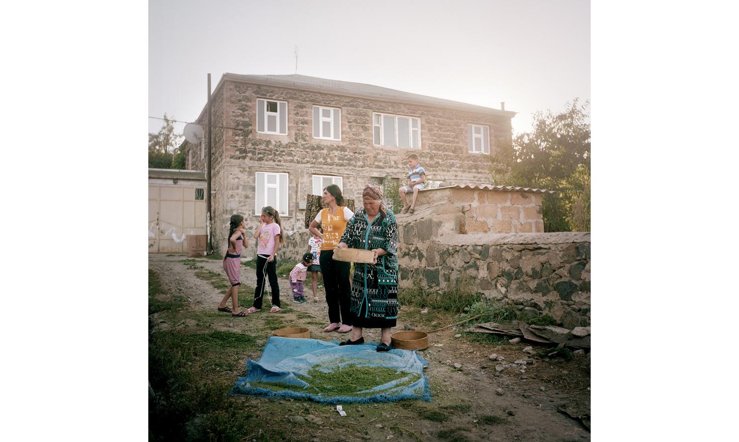 An everyday scene in a small street of the village: a lady is sorting hemp seeds that she'll use for cooking later.