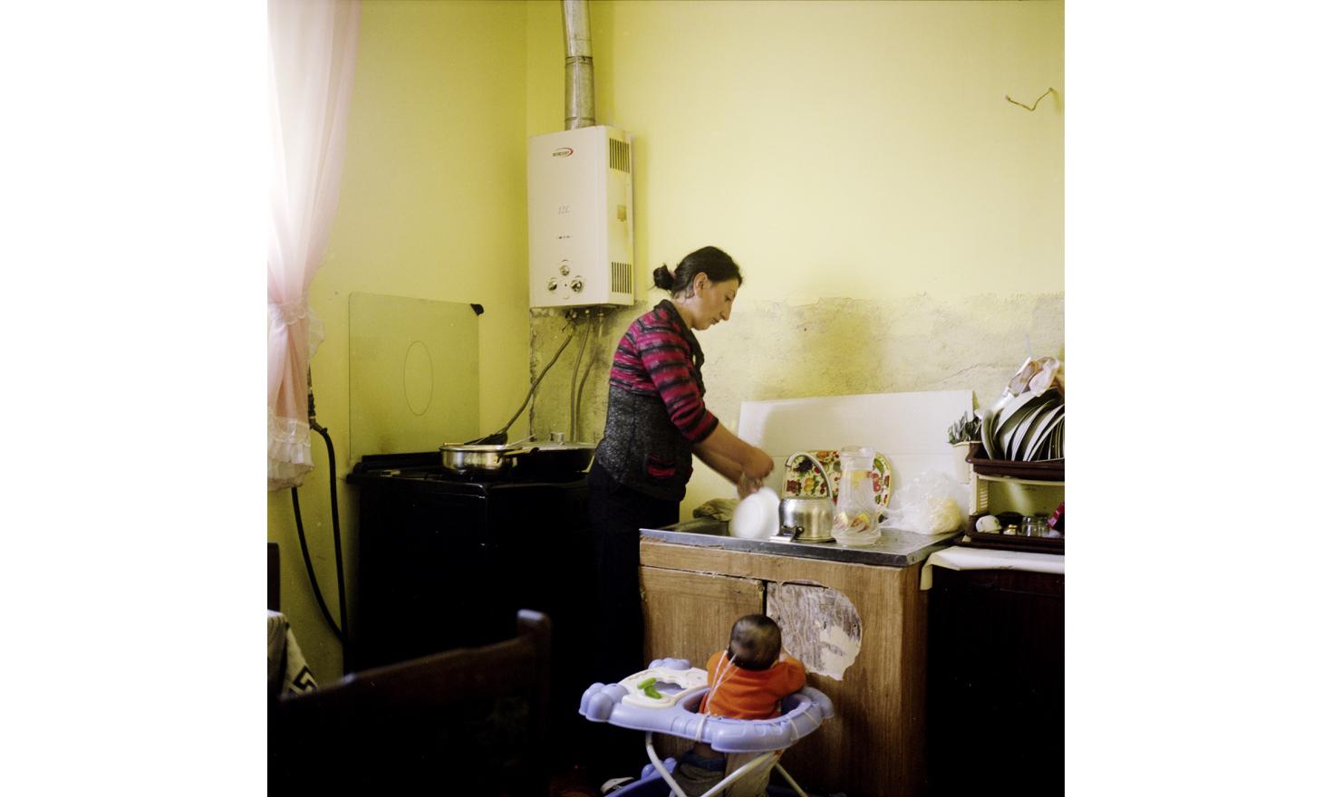 At Anoush's and Ruzanna's house. Ruzanna is doing the dishes while she must keep a look on her young daughter Naïre