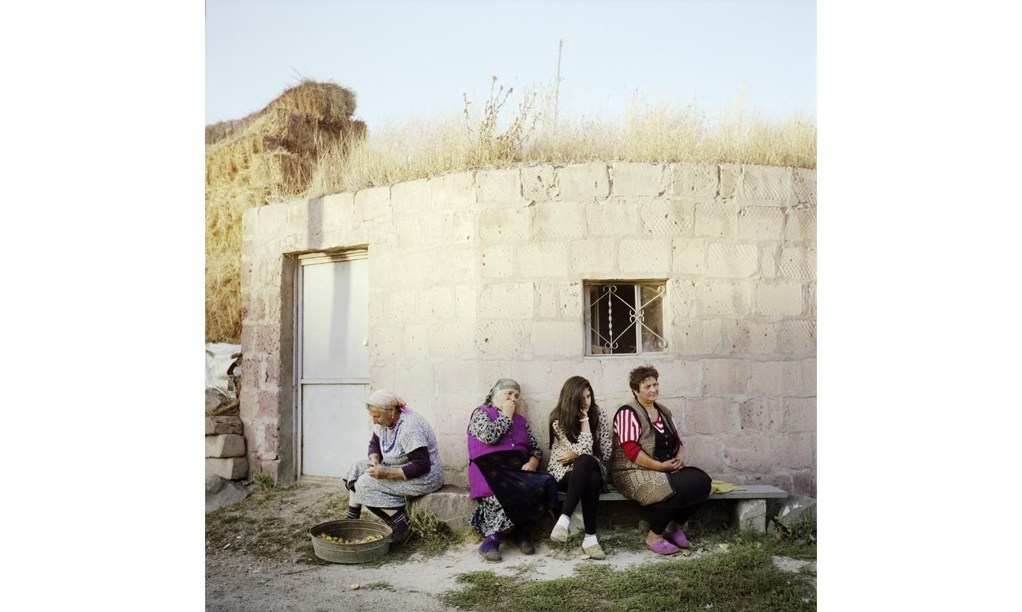 Daily life in the village streets. Tonight the women gather to chat while one of them sorts some fruits.