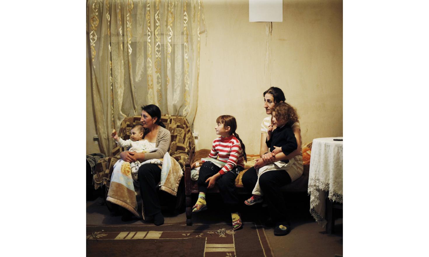 Anoush and Ruzanna are watching TV with three of their children.